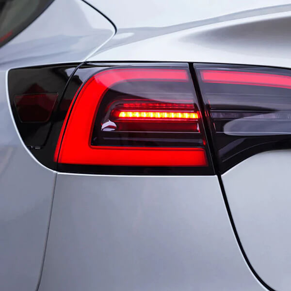 Close view of an illuminated rear lamp on a silver Tesla