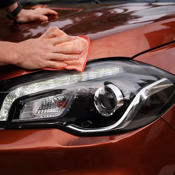 Technician cleaning paint beside a headlamp before film application