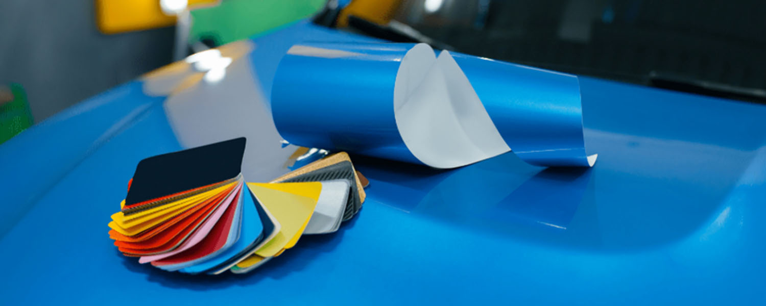 Vinyl color swatches and a blue film roll on a car hood