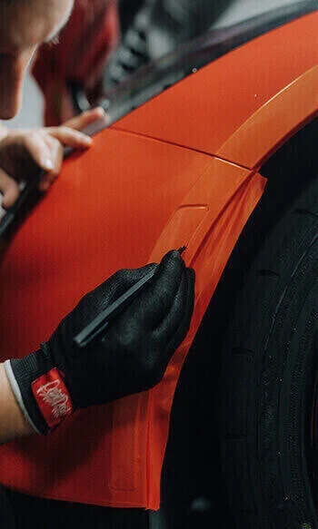 Installer working vinyl around a wheel arch