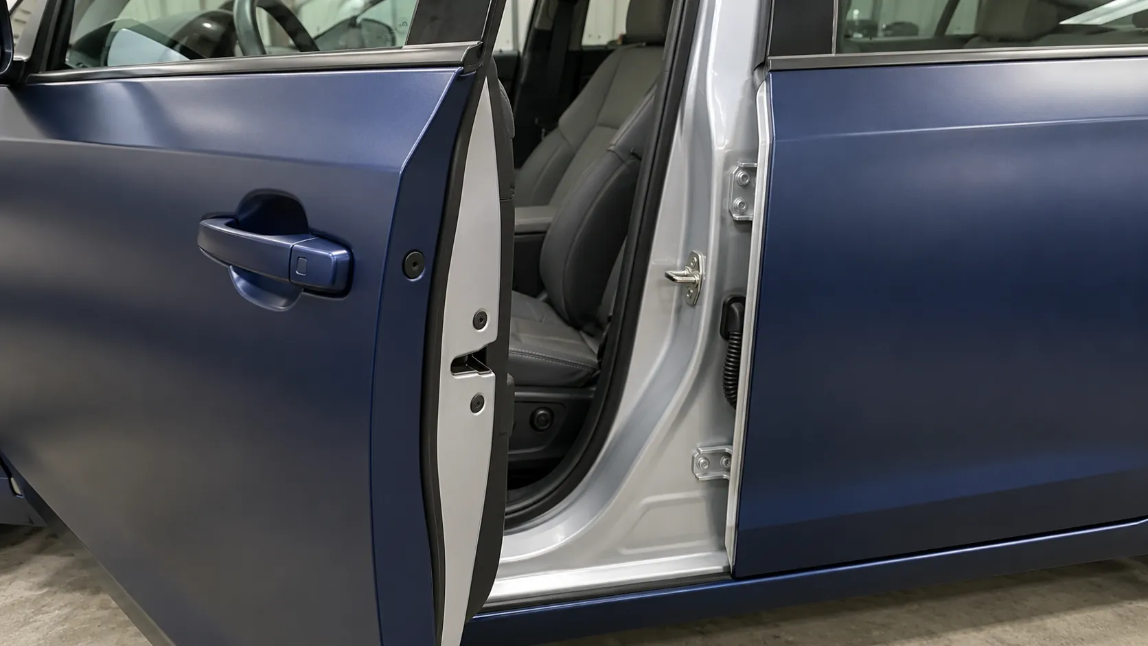 Open car door showing navy outer panels and silver painted door-jamb areas