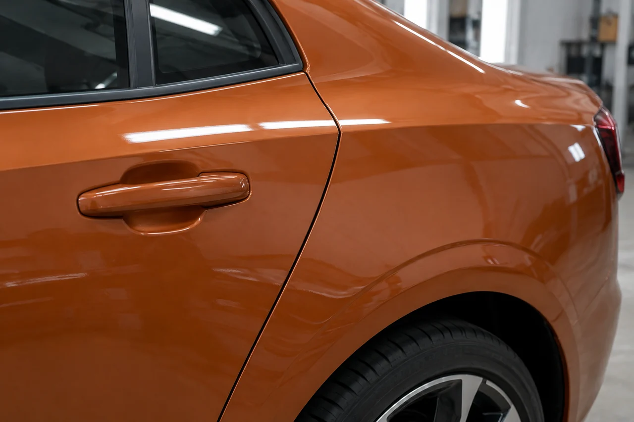 Orange wrapped rear door and quarter panel with an intact panel gap and wheel-arch edge