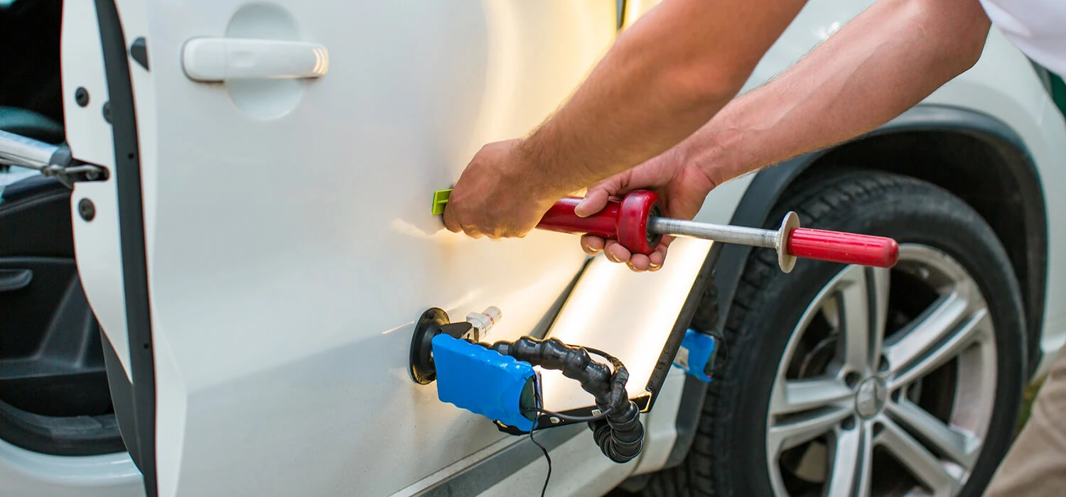 Dent-pulling tool and reflection light in use on a white vehicle door