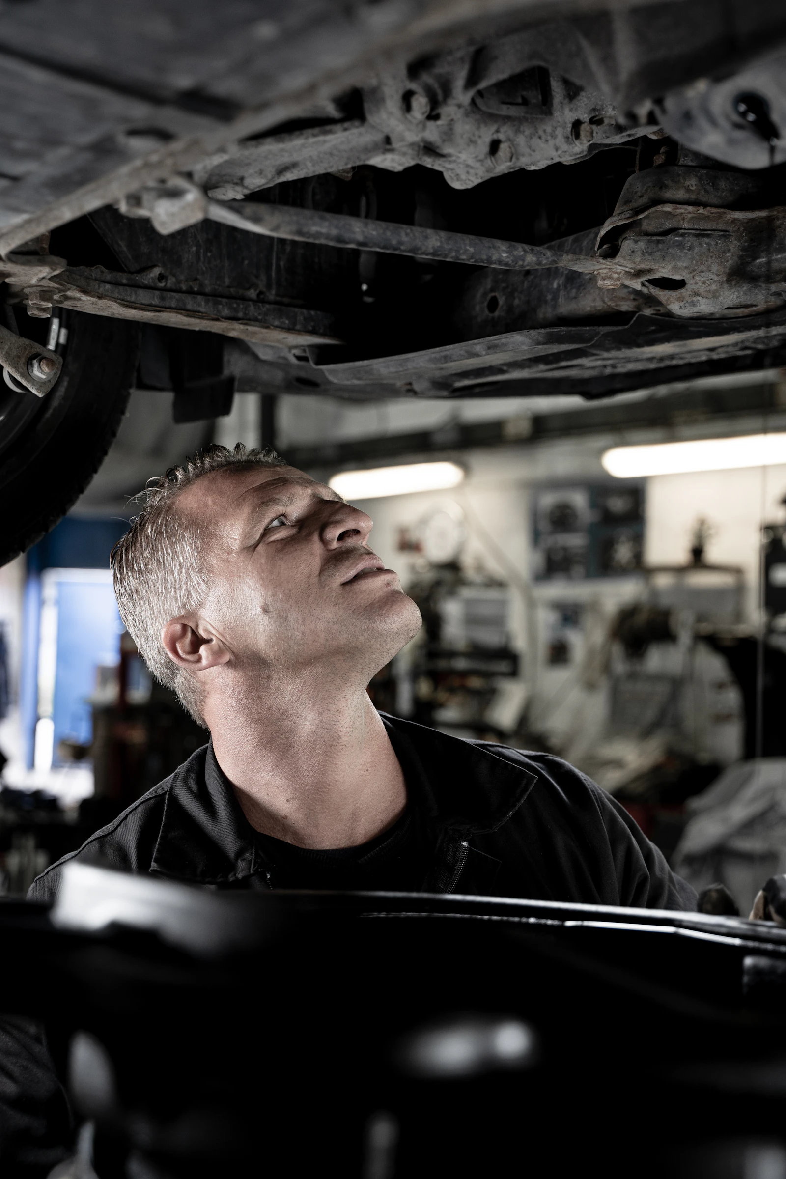 Mechanic checking the accessible underside of a raised vehicle