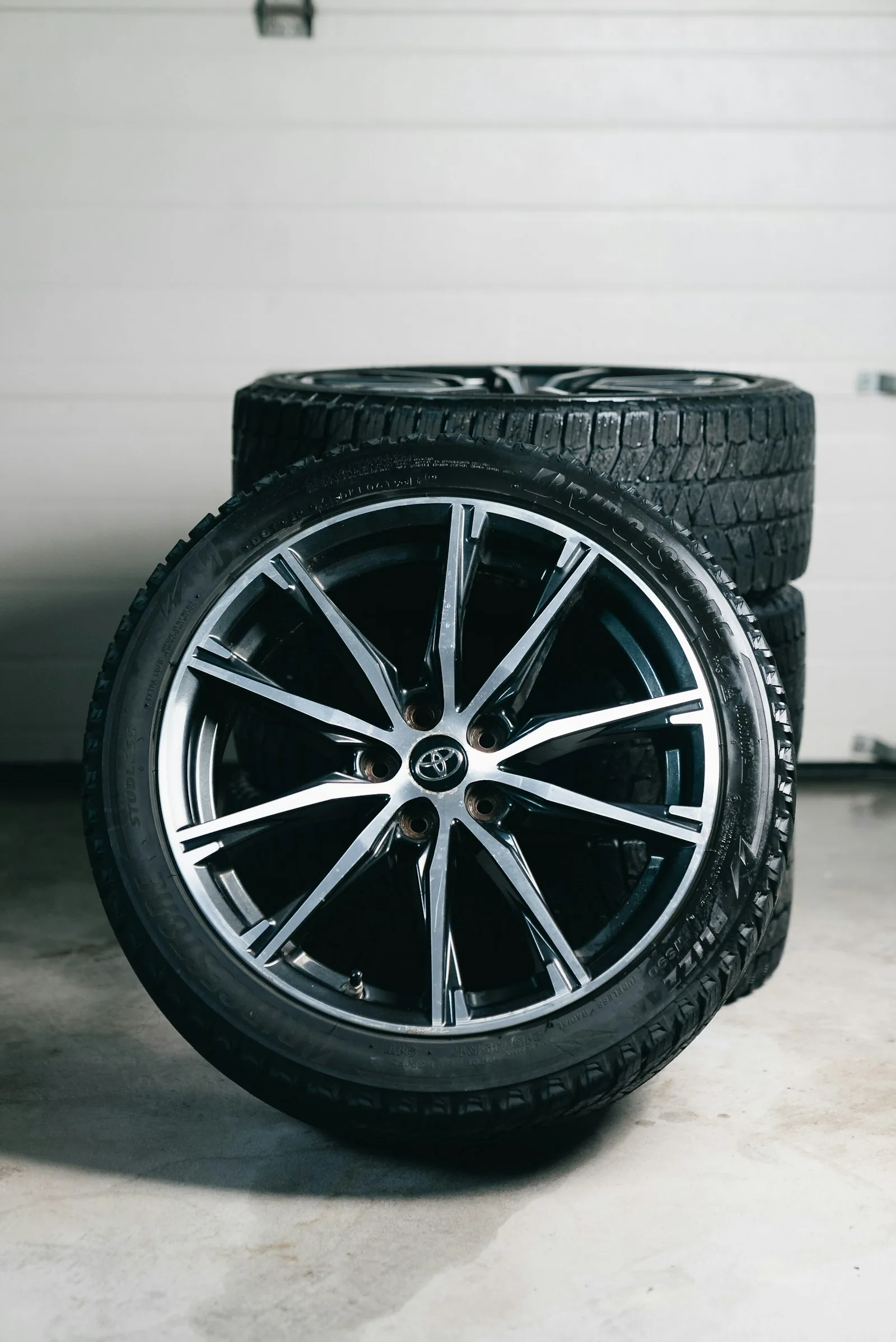 Black and silver alloy wheel beside stacked tires