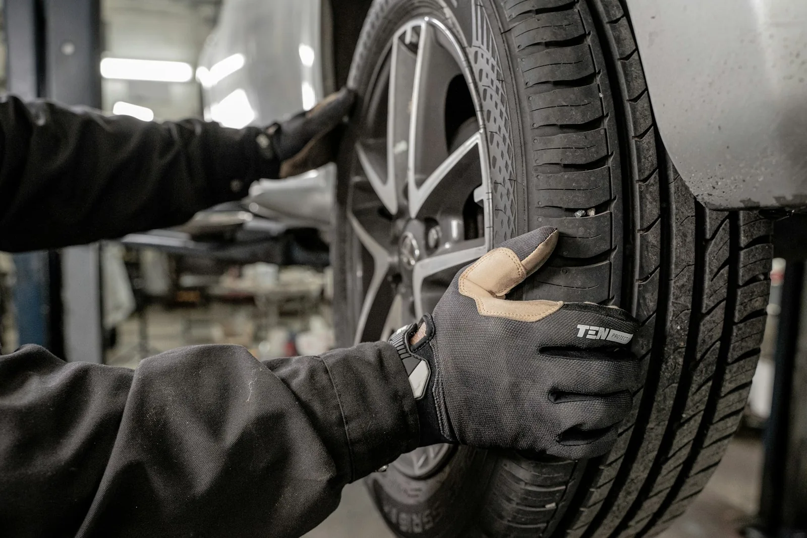 Gloved hands positioning an alloy wheel on a vehicle
